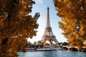 Herbstliche Morgensonne beleuchtet den Eiffelturm in Paris, eingerahmt von goldgelbem Laub an der Seine.