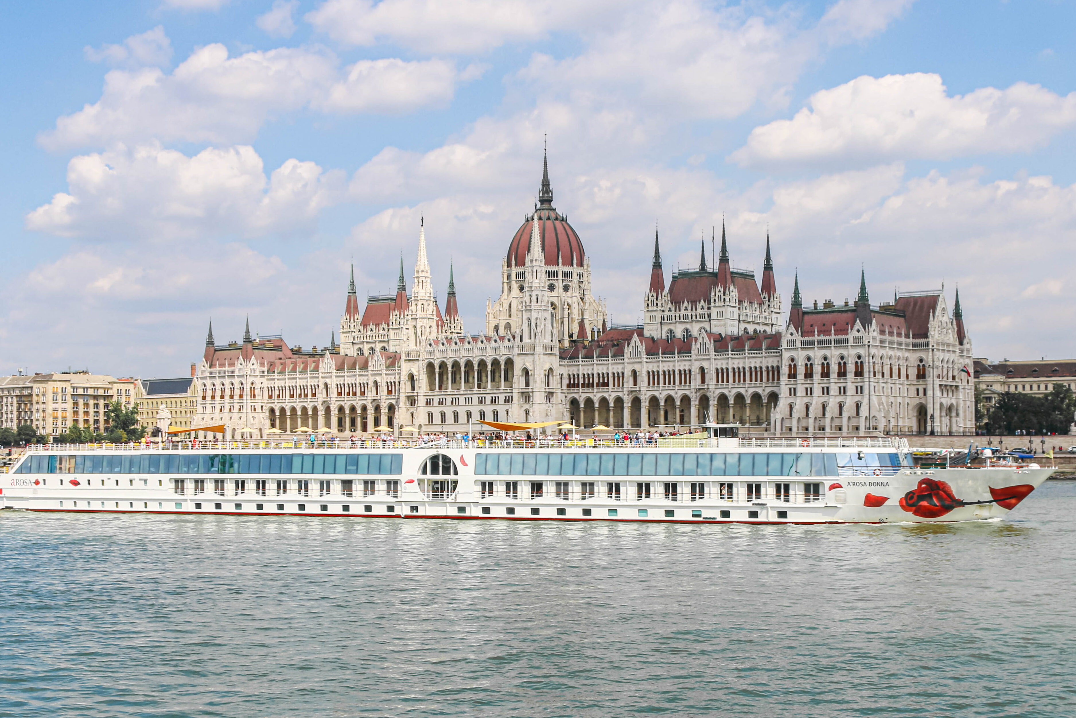 Panorama der ungarischen Nationalversammlung in Budapest mit einem Flusskreuzfahrtschiff im Vordergrund.