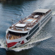 Luxuriöses Flusskreuzfahrtschiff - die A-ROSA ALVA - mit Sonnendeck und Pool, das sanft über ein Gewässer fährt.