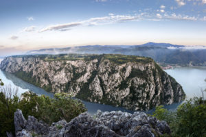 Die Donau schlängelt sich zwischen steilen Felswänden durch das beeindruckende Eiserne Tor, umgeben von dicht bewaldeten Hügeln.