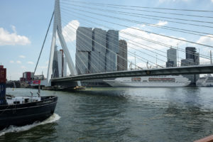 Erasmusbrücke in Rotterdam mit moderner Architektur, Schiffen auf dem Fluss und Hochhäusern im Hintergrund