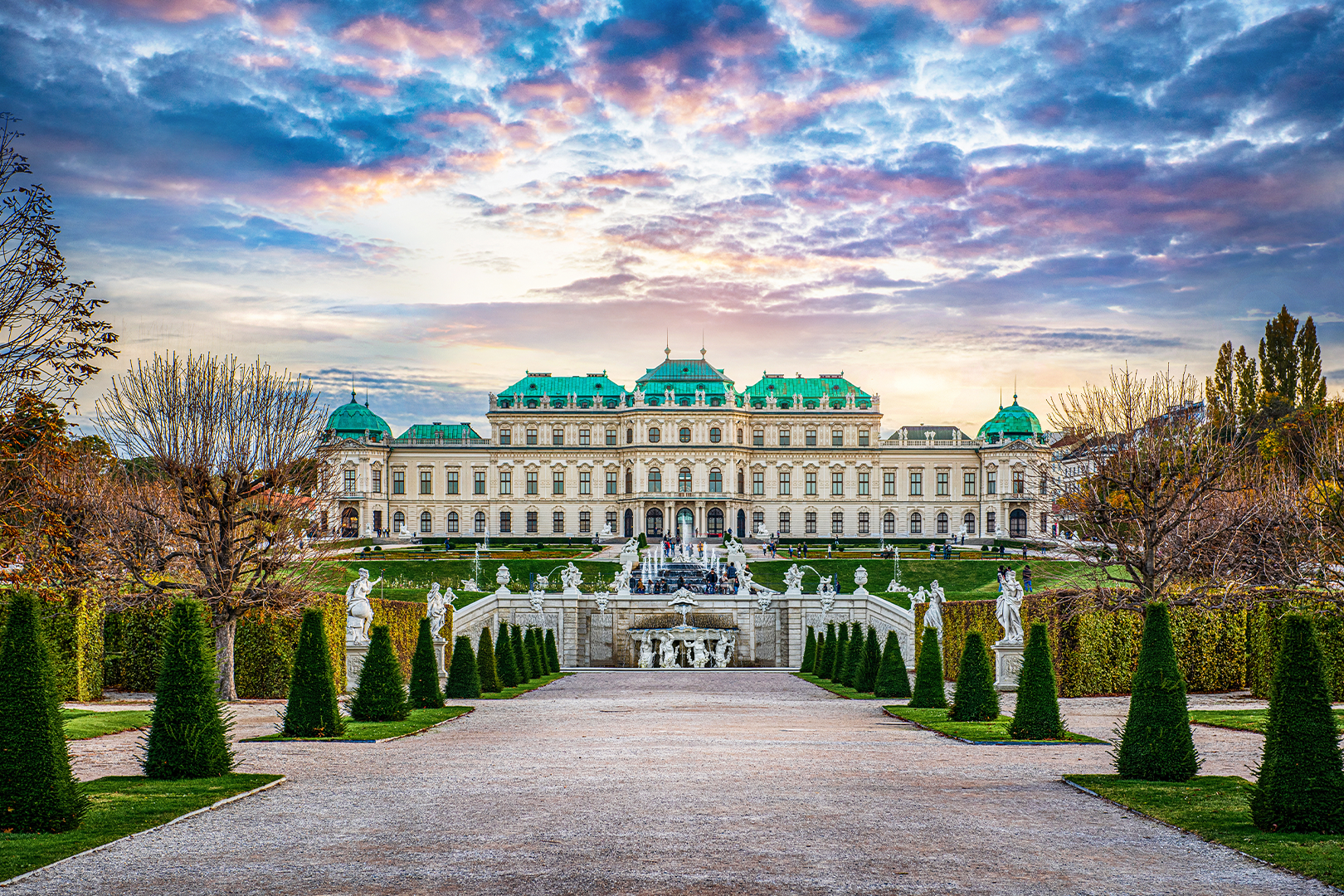 Barockes Schloss Belvedere in Wien mit grünen Dächern, symmetrischem Garten und Statuen bei Sonnenuntergang