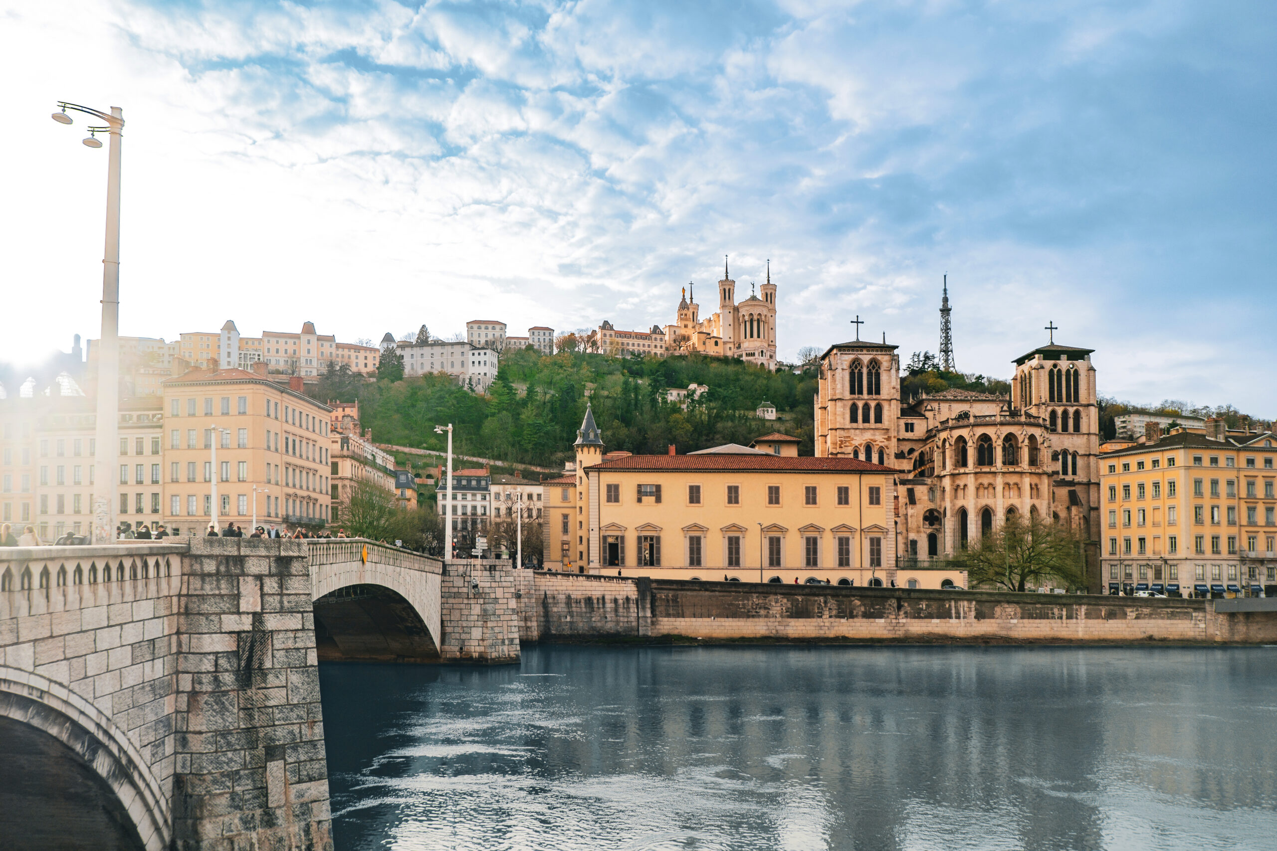 Blick am späten Nachmittag über die Saône auf die Altstadt von Lyon mit Kathedrale, Basilika und dicht stehenden Fassaden am Hang.
