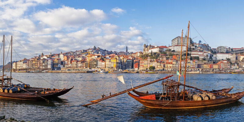 The iconic Rabelo Boats, the traditional Port Wine transports, with the Ribeira District and the Dom Luis I Bridge over the Douro River. Porto, Portugal. Unesco World Heritage.
Porto, Rabelo, boats, Douro, river, boat, rabelos, Port, Wine, Ribeira, district, Oporto, Dom, Luis, I, bridge, old, antique, vintage, tradition, traditional, Vila, Nova, de, Gaia, Portugal, Portuguese, Europe, European, water, transport, transportation, historic, historical, sunset, day, daylight, blue, sky, white, clouds, Unesco, world, heritage, site, rio, Duero, nobody, panorama, panoramic